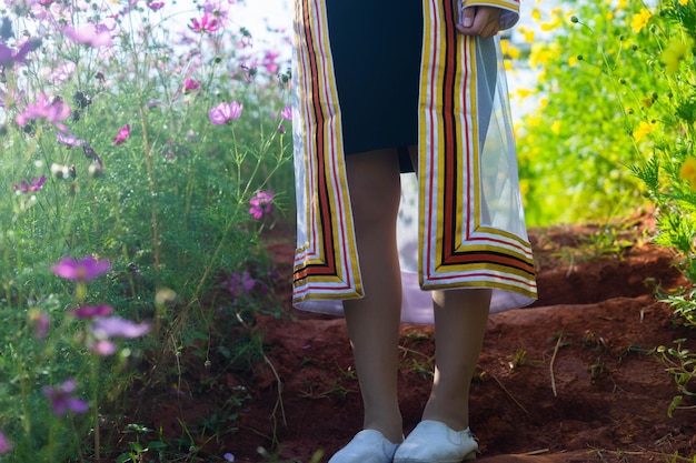 Seção baixa de mulher de pé em plantas com flores