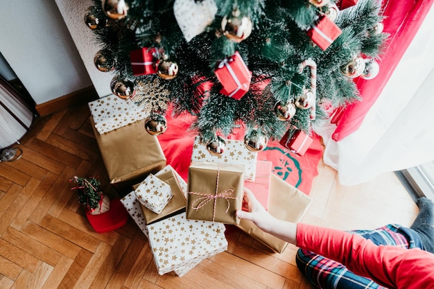 Seção baixa de mulher mantendo presente pela árvore de Natal