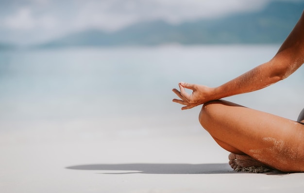 Seção baixa de mulher meditando na praia