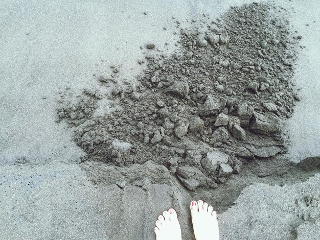 Foto seção baixa de mulher na areia molhada na praia