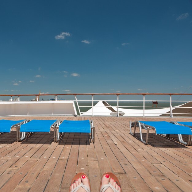 Seção baixa de mulher relaxando em um navio de cruzeiro contra o céu