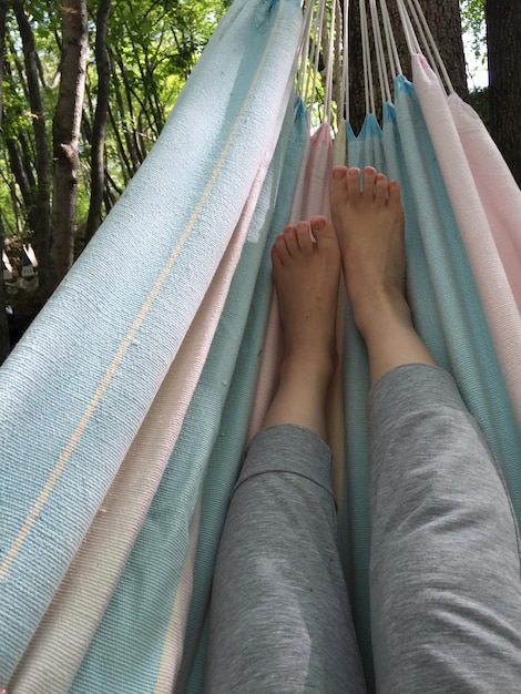 Foto seção baixa de mulher relaxando em uma hamaca na floresta