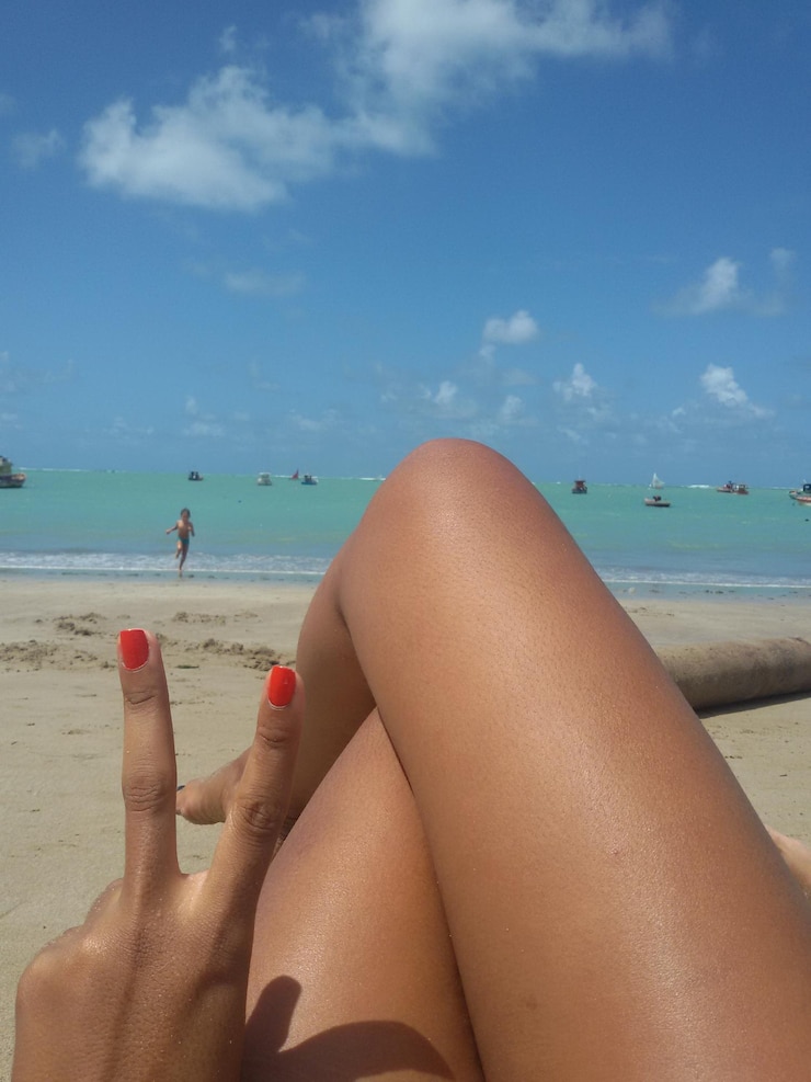 Foto seção baixa de mulher relaxando na praia contra o céu