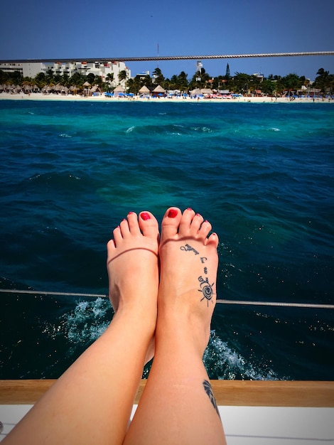 Seção baixa de mulher sentada em um barco sobre o mar durante um dia ensolarado