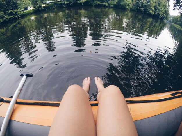 Foto seção baixa de mulher sentada em uma jangada inflável no lago