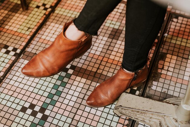 Foto seção baixa de mulher vestindo sapatos castanhos no chão de telhas