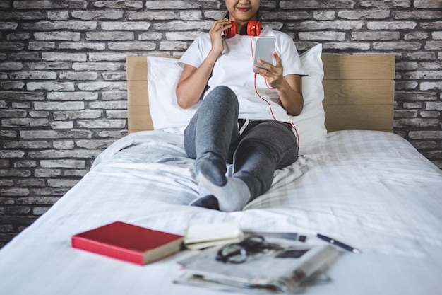 Seção baixa de mulheres usando telefone móvel na cama em casa