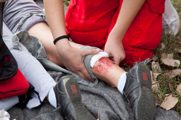 Foto seção baixa de paramédico sentado por mulher ferida no campo