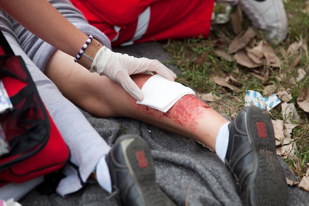 Foto seção baixa de paramédico sentado por mulher ferida no campo