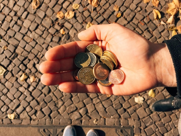 Foto seção baixa de pessoa com moedas de pé na rua durante o dia ensolarado