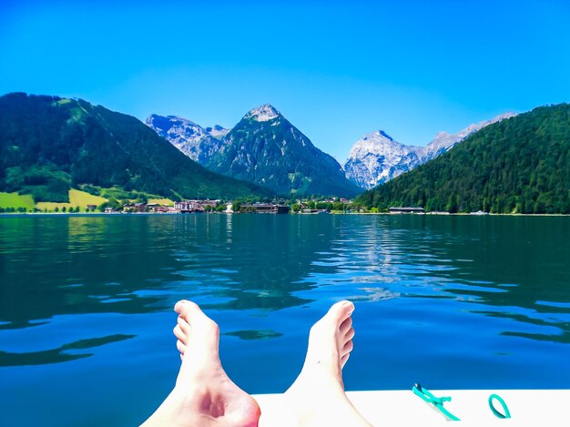 Foto seção baixa de pessoa contra lago e montanhas