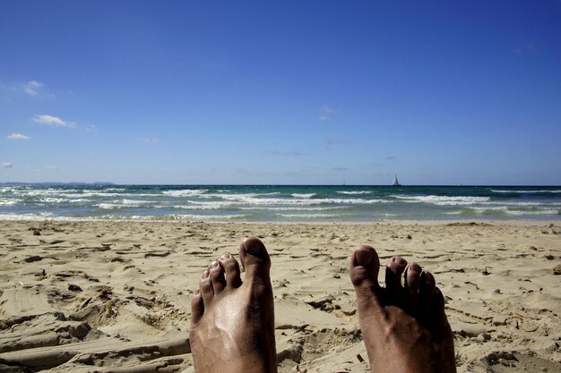 Foto seção baixa de pessoa na praia contra o céu