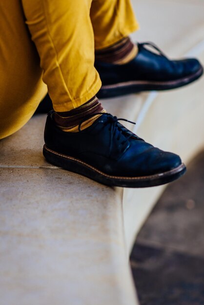 Foto seção baixa de pessoa vestindo sapatos pretos sentada em degraus