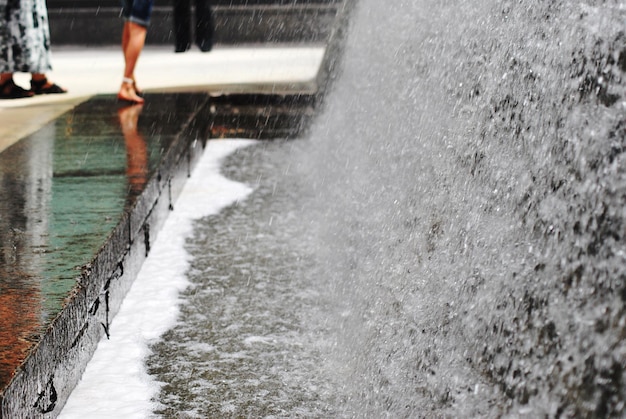 Foto seção baixa de pessoas de pé junto à cachoeira