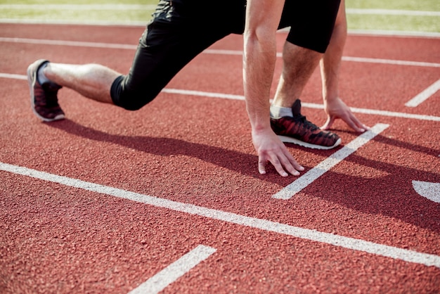 Seção baixa de um atleta do sexo masculino na linha de partida da pista de corrida