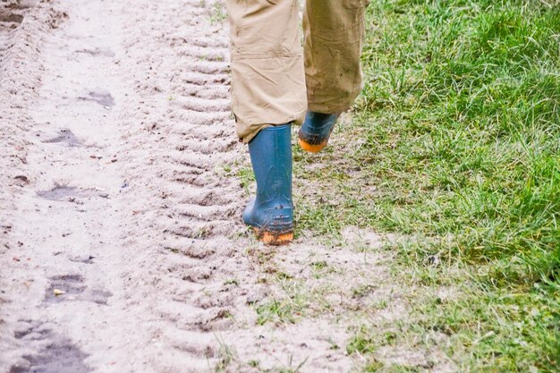 Seção baixa de um homem caminhando em uma estrada de terra