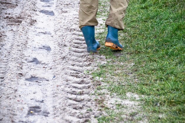 Seção baixa de um homem caminhando em uma estrada de terra