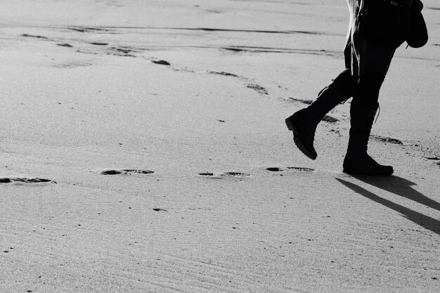 Foto seção baixa de um homem caminhando na areia na praia