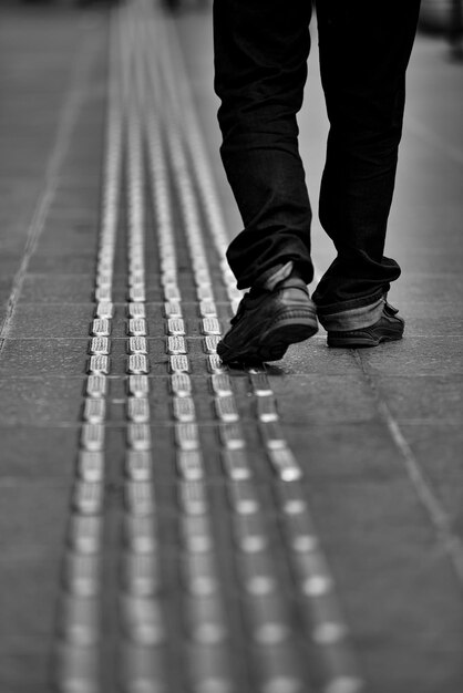 Foto seção baixa de um homem caminhando por uma calçada