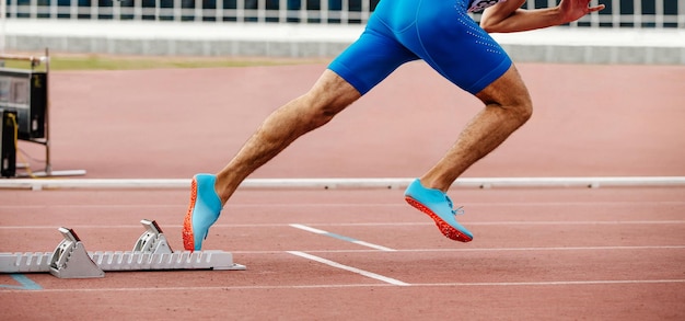 Seção baixa de um homem correndo na pista no estádio