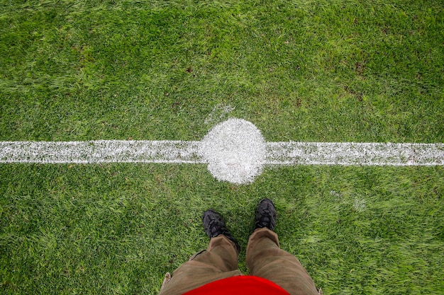 Seção baixa de um homem de pé em um campo de futebol