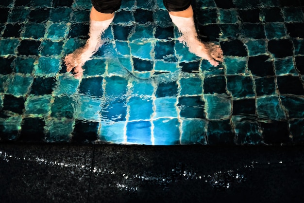 Seção baixa de um homem de pé junto à piscina