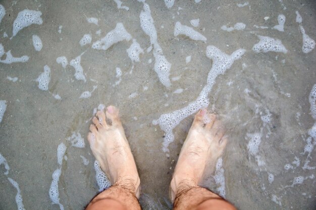 Foto seção baixa de um homem de pé na costa na praia