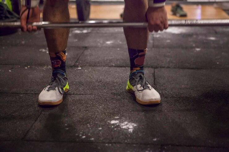 Foto seção baixa de um homem levantando halteres no ginásio