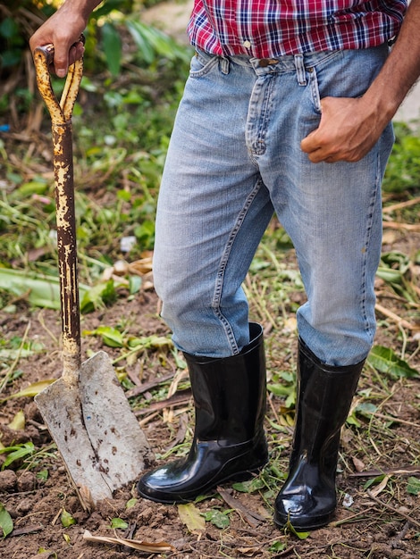 Foto seção baixa de um homem segurando uma pá enquanto está de pé em terra