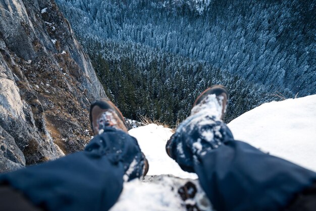 Foto seção baixa de um homem sentado em uma montanha coberta de neve sobre árvores