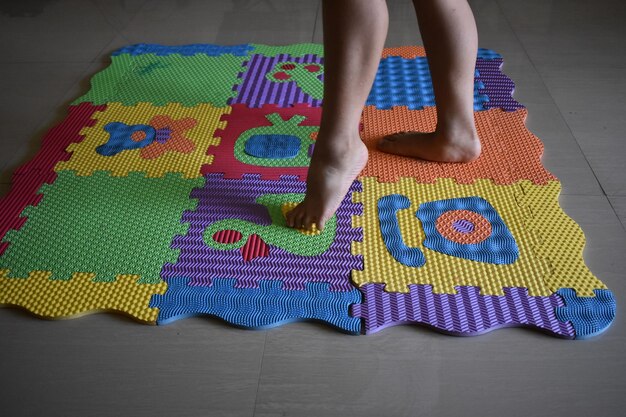 Seção baixa de um menino caminhando em tapete multicolorido