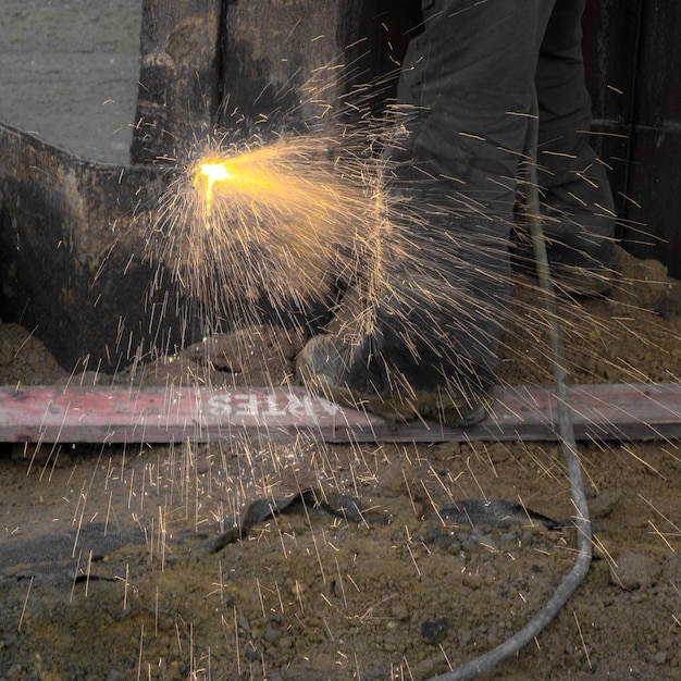 Foto seção baixa de um trabalhador masculino moendo metal em uma fábrica