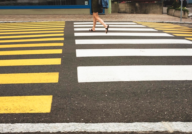 Foto seção baixa de uma mulher caminhando em uma passagem de zebra