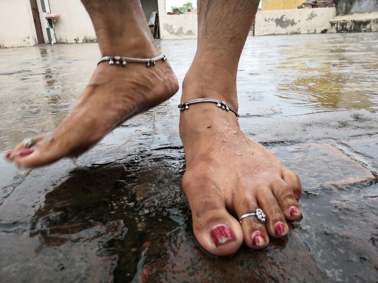 Foto seção baixa de uma mulher de pé em uma calçada molhada