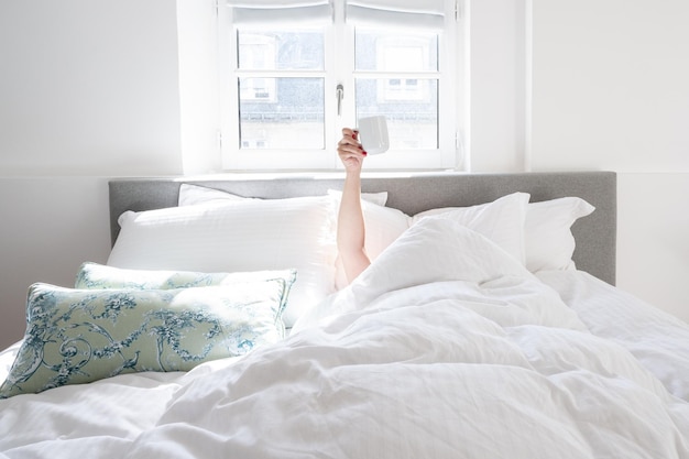 Seção baixa de uma mulher dormindo na cama em casa - xícara de café no ar