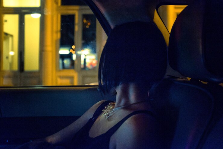Foto seção baixa de uma mulher sentada em um carro à noite