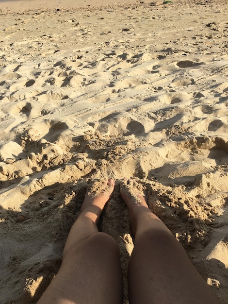 Seção baixa de uma pessoa de pé em uma praia de areia