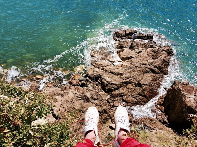 Foto seção baixa de uma pessoa no penhasco sobre o mar