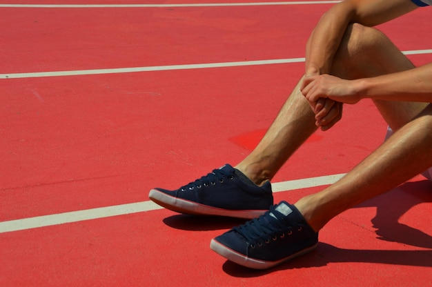 Seção baixa do atleta sentado na pista