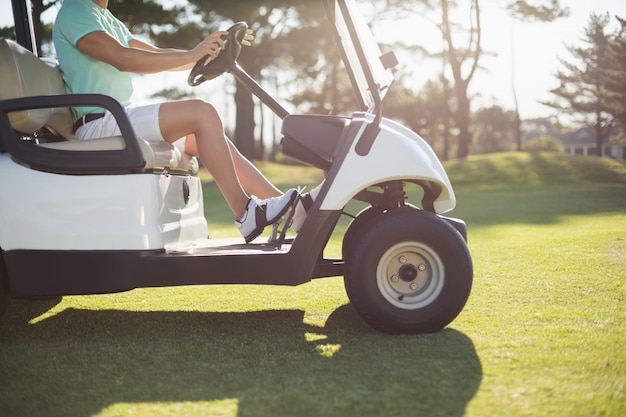 Seção baixa do homem golfista dirigindo carrinho de golfe