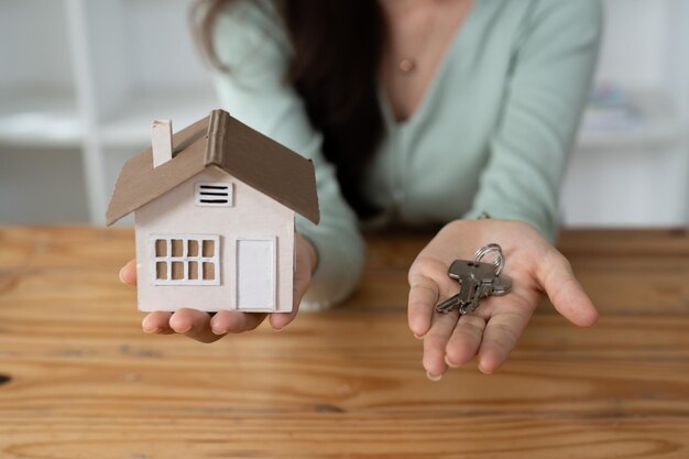 Seção central de uma mulher segurando uma casa modelo