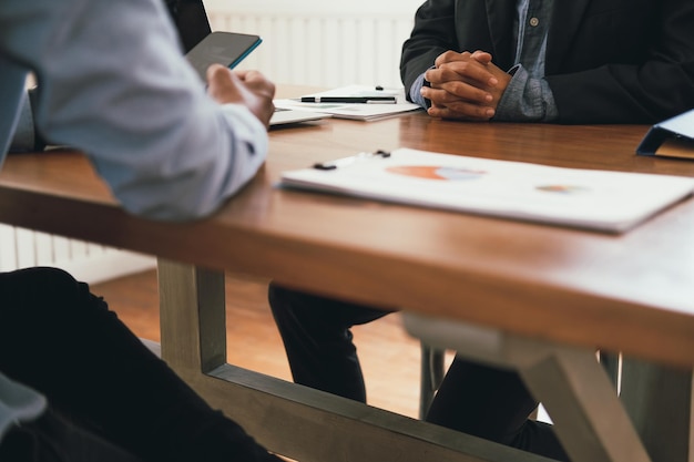 Seção do meio de um empresário e colegas trabalhando sobre um gráfico na mesa