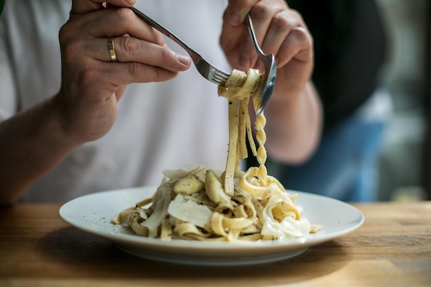 Seção do meio de um homem comendo macarrão