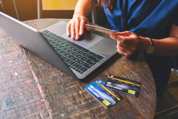 Foto seção do meio de uma mulher segurando um cartão de crédito enquanto usa um laptop em um café