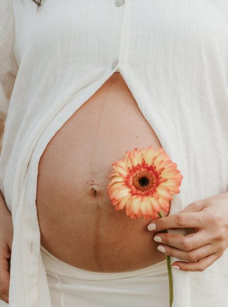 Foto seção do meio de uma mulher segurando uma flor