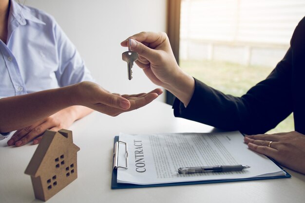 Foto seção do meio do agente imobiliário dando a chave ao cliente na mesa