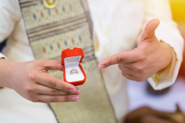 Seção do meio do noivo segurando o anel de casamento durante a cerimônia