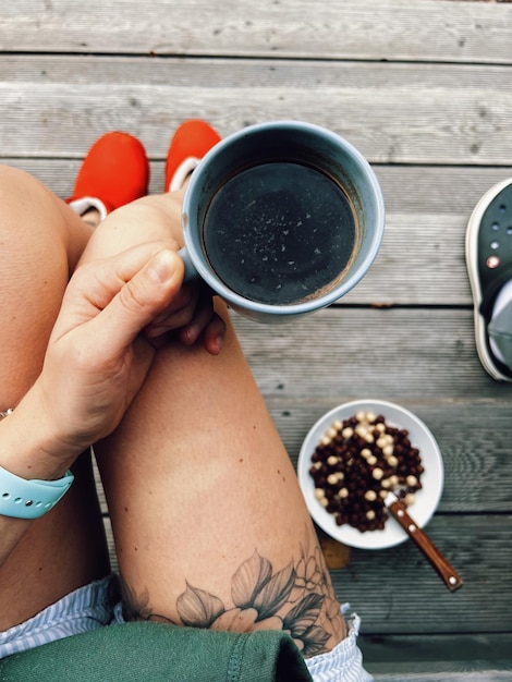 Foto seção inferior da mulher segurando café na mesa