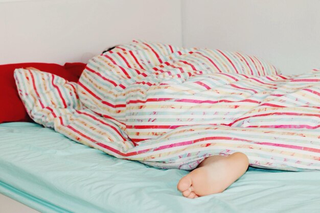 Foto seção inferior da pessoa a dormir na cama em casa