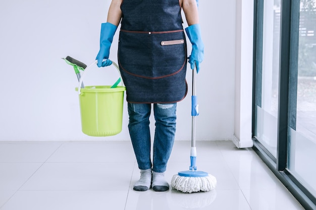 Seção inferior de mulher com equipamento de limpeza em casa